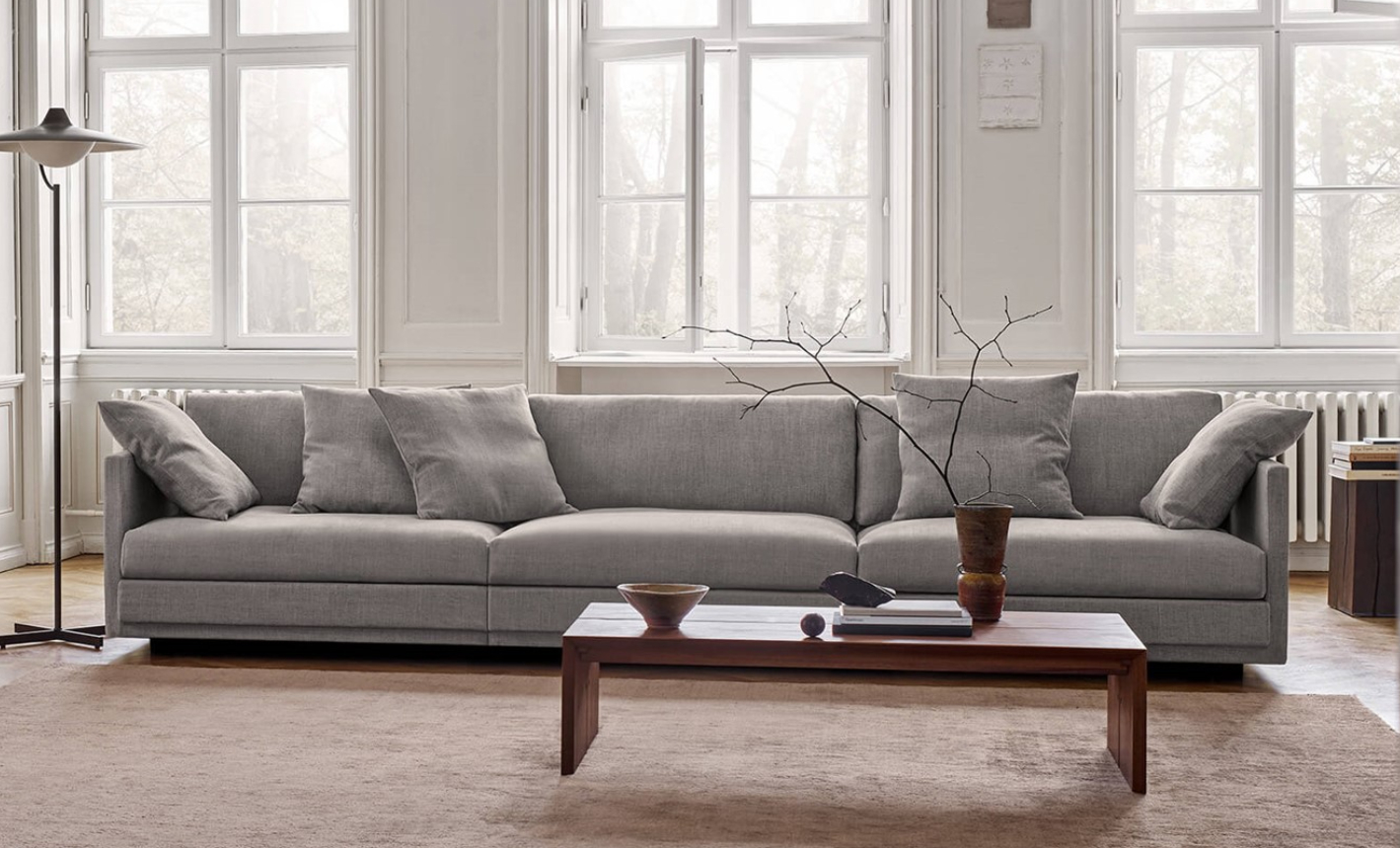 Eilersen Great Ash Sofa in grey upholstery styled in a classic Scandinavian living room with tall windows.