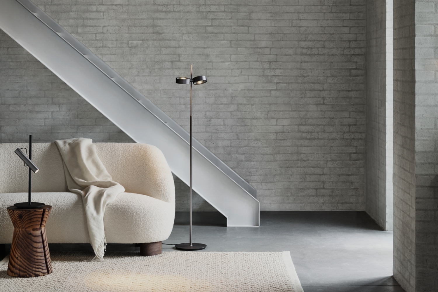 Light-Point Copenhagen EDGE Orbit pendant and matching EDGE floor lamp, delivering precise, directional lighting in a modern dining and living area with exposed brick walls.