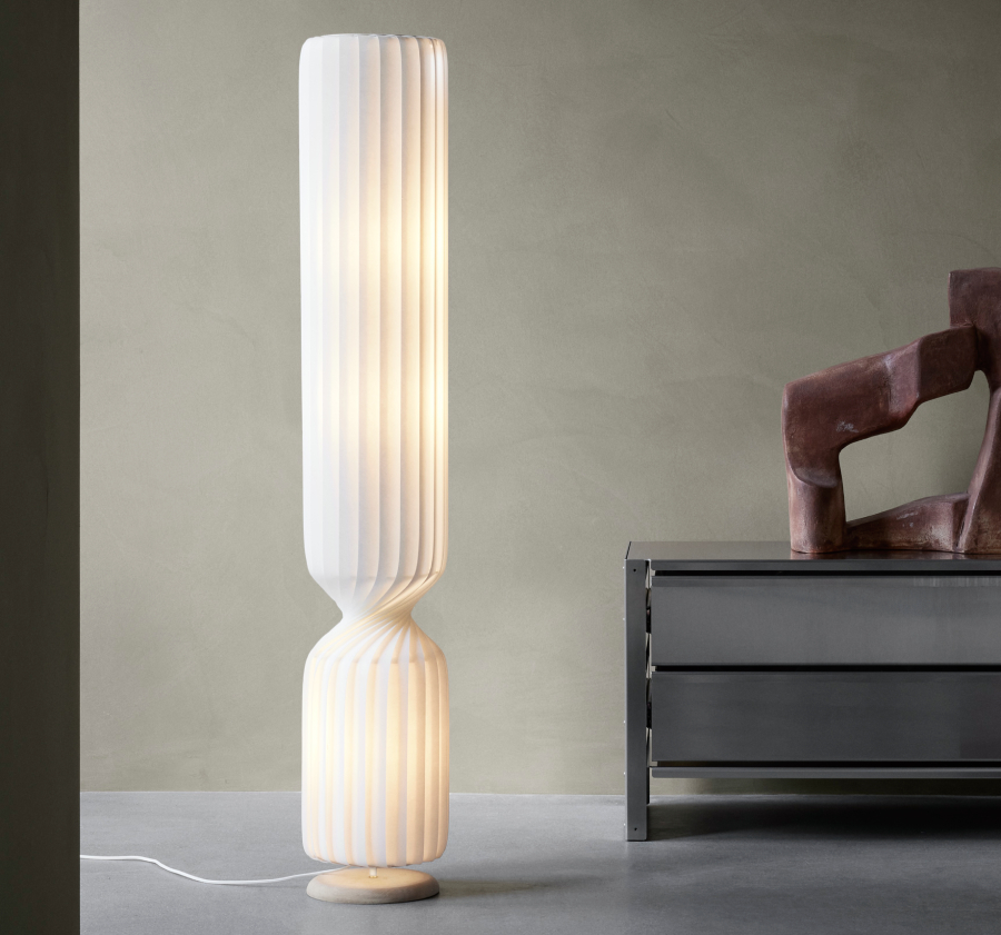Tom Rossau TR41 floor lamp in a soft white finish, designed with a tall cylindrical form and layered curved slats that gently diffuse light beside modern furniture.