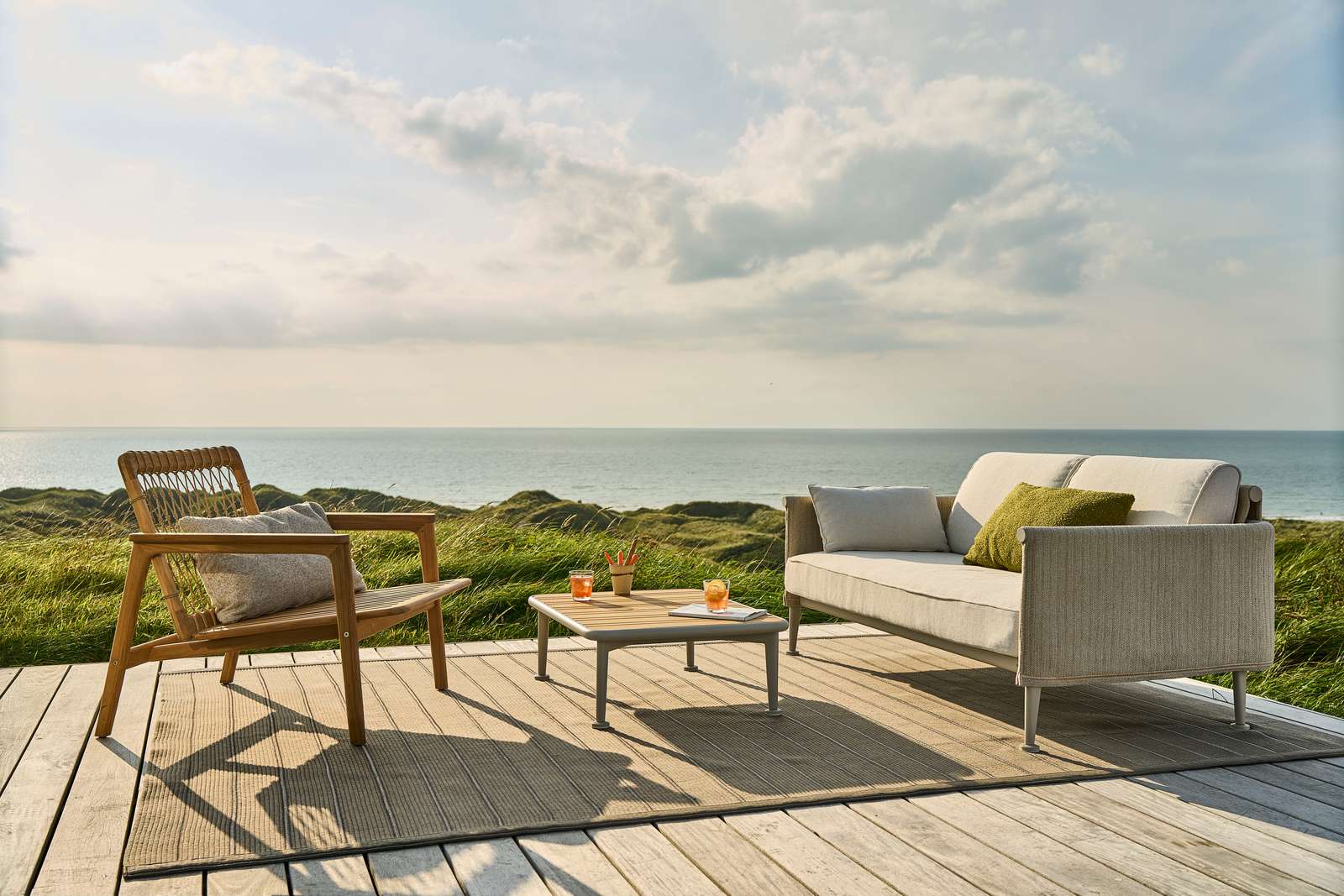 Mindo 123 teak lounge chair with woven cord backrest and cushions on a coastal deck overlooking the sea &mdash; part of the Mindo 123 outdoor furniture collection by Mindo.