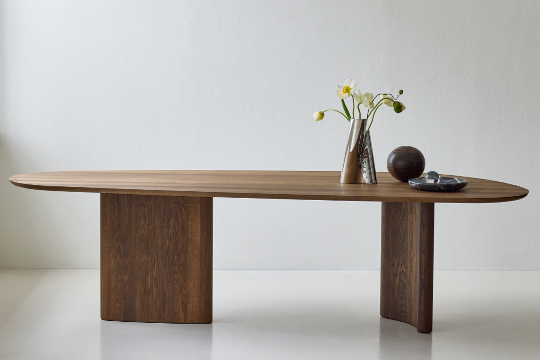 Minimal side profile of the DK3 Tangent Table in smoked oak, with simple sculptural d&eacute;cor placed along the tabletop.